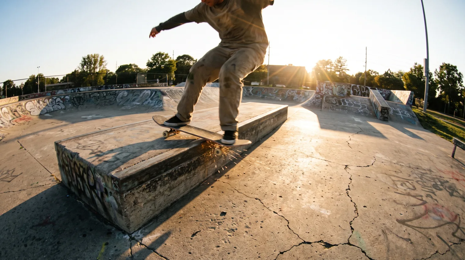 A skateboarder grinding a ledge in a 50-50 stance, trucks balanced on the edge